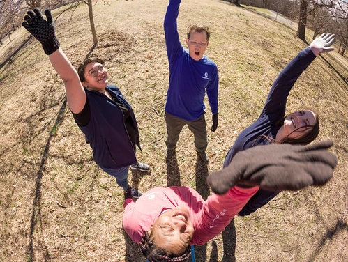 Four young adults standing outdoors in a circle high-fiving