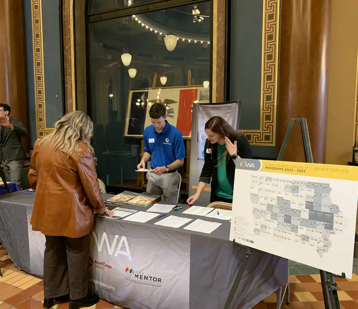 Three adults standing at a table reviewing brochures