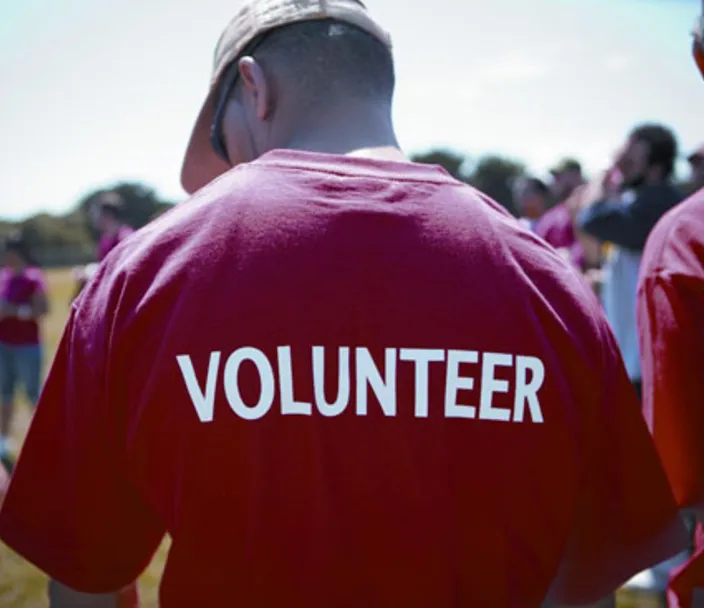 Back of adult male wearing a red t-shirt with the word volunteer on it