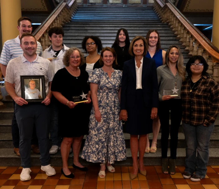 A group of individuals honored with Excellence in Mentoring Awards standing on the Iowa Capital main staircase