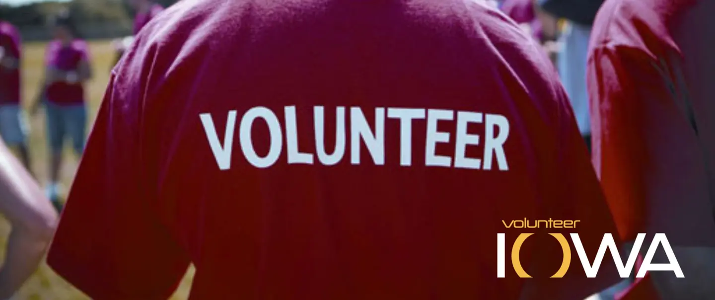 The back of an adult wearing a red t-shirt with the word volunteer on it