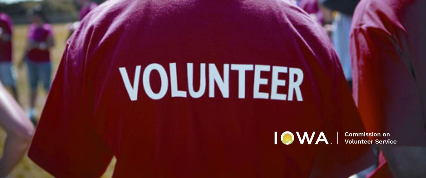 The back of a person wearing a burgundy tshirt with the word volunteer on it in white