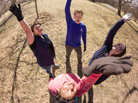 Four young adults standing outdoors in a circle high-fiving