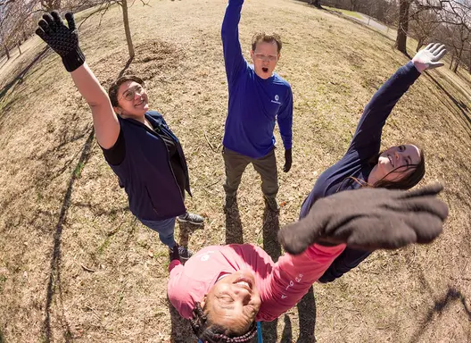Four young adults standing outdoors in a circle high-fiving