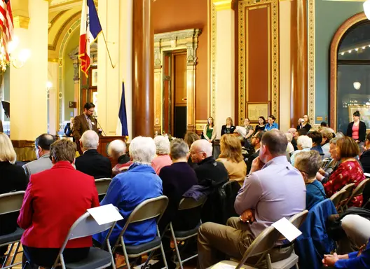 Individuals seated in chairs facing towards a podium at a volunteer recognition event