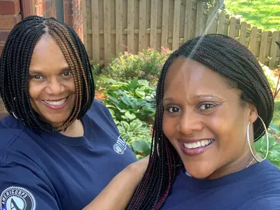 Two women standing in a garden wearing navy AmeriCorps VISTA shirts
