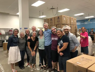 Group of adults wearing hair nets preparing for meal packing