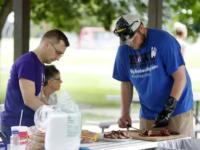 Two adult men serving food at a volunteer event