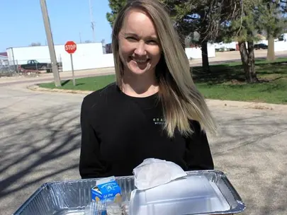 Woman with long blond hair holding a tray of food to be delivered
