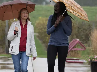 Two women holding umbrellas walking outdoors on a sidewalk in the rain